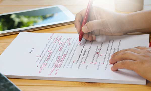 Hand proofreading text using a red pen